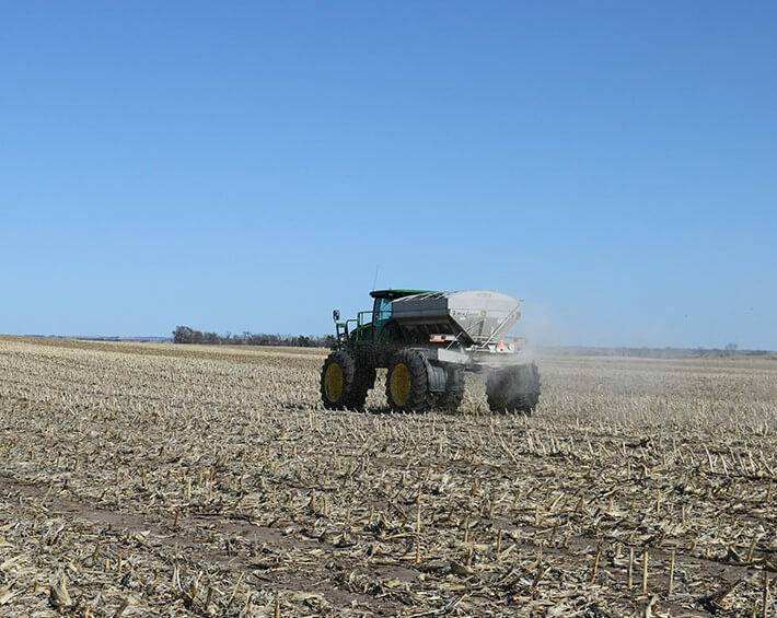 A John Deere tractor driving through an empty field preparing for planting season