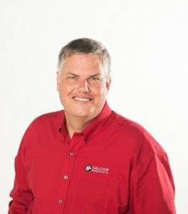 Glen Howell smiling from the chest up in a red Calcium Products shirt in front of a white background