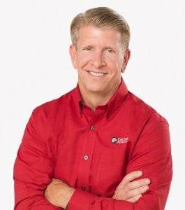 Mike Hogan smiling with his arms crossed while wearing a red button-up Calcium Products shirt in front of a white backdrop