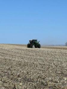 A green John Deere tractor is releasing 98G fertilizer onto a field so crops can effectively grow